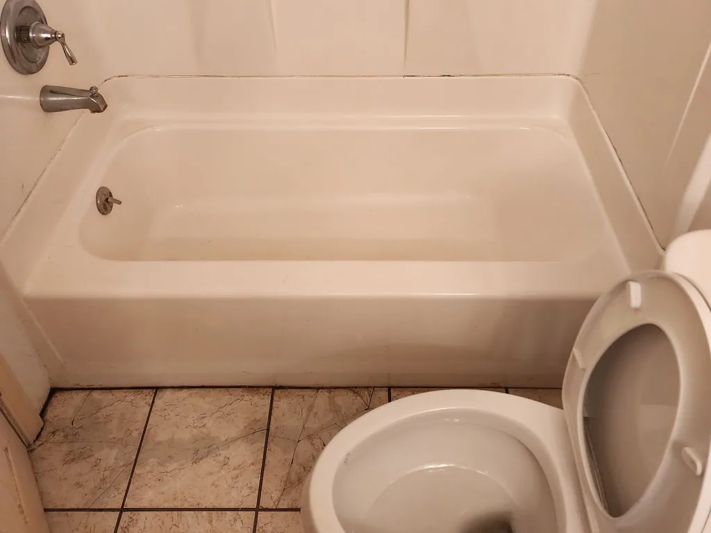 The same bathtub and toilet cleaned to a bright white finish after a deep cleaning.